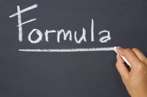 Hand writes formula on blackboard